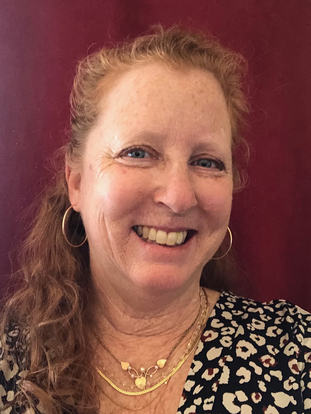 Polly Andrews Photo of Polly Andrews, a woman with red hair, wearing a black and white dress, smiling